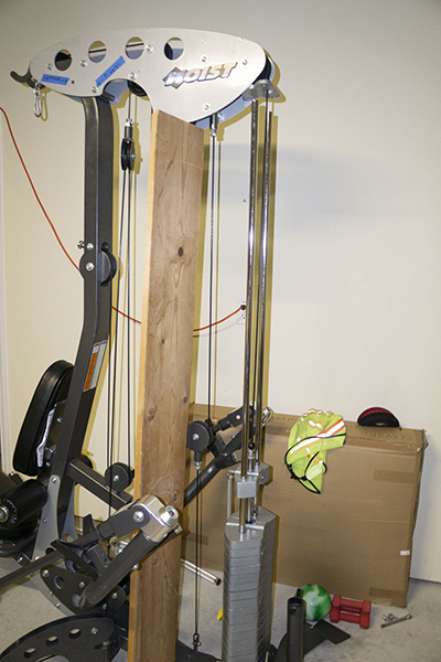 Photograph of Hoist Fitness V5 vertical gym showing "top mainframe assembly" propped up with a board so that the weight stack can be removed.